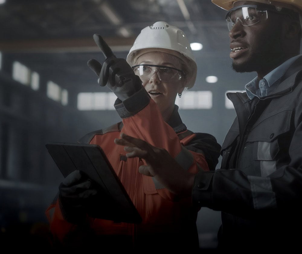 Two industrial workers in safety gear discussing safety protocols.