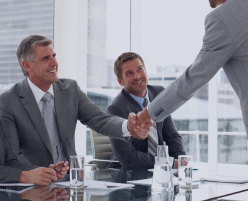 Executive candidate shaking hands with hiring panel during a leadership interview, guided by insights from a recruitment agency.