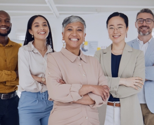 Diverse executive leadership team standing confidently in a modern office, representing how a recruitment agency supports inclusive executive hiring.
