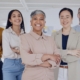 Diverse executive leadership team standing confidently in a modern office, representing how a recruitment agency supports inclusive executive hiring.