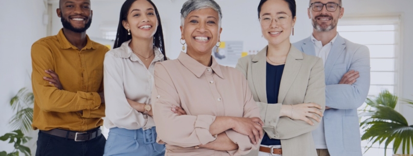 Diverse executive leadership team standing confidently in a modern office, representing how a recruitment agency supports inclusive executive hiring.