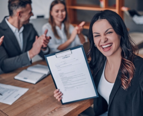 Successful job candidate holding a signed contract while colleagues applaud, highlighting how a Recruitment agency Durban connects talent with real job opportunities in Durban and KZN.